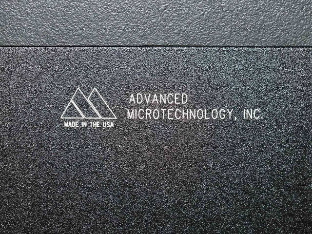 Close-up of Advanced Microtechnology Inc. embossed logo plate on burn-in system cabinet — Made in the USA