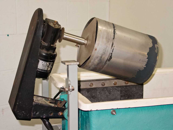 Left-end circulator motor and stainless steel drum assembly mounted on tank side — motor visible with label, drum shows surface peeling and wear