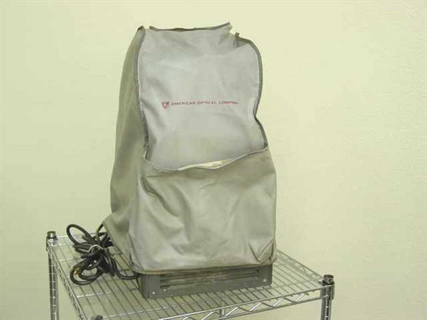 American Optical 3525 HS Delineascope opaque projector with original American Optical Company gray fabric dust cover fitted over unit, on wire shelf
