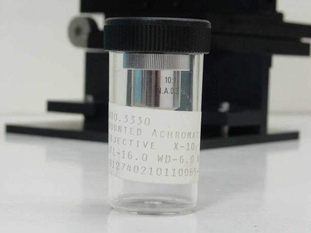 Rolyn Germany 10x N.A. 0.30 mounted achromat objective stored in its protective clear plastic vial — label shows X-10, FL-16.0, WD-6.0 specifications