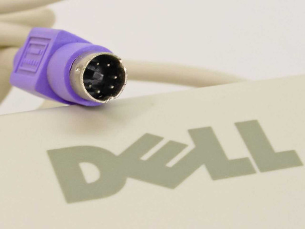 Close-up of purple PS/2 mini-DIN 6-pin connector resting on Dell AT101W keyboard case with embossed Dell logo