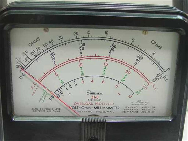 Simpson 260 Series 6P dial close-up — tri-color arc scale showing Ohms (top), DC/AC voltage, AC current, and dB ranges with mirrored parallax-prevention strip; 'Overload Protected Volt-Ohm-Milliammeter' legend visible