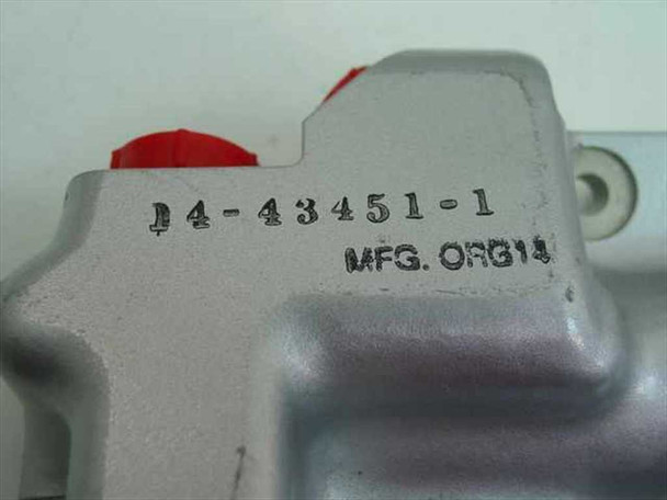 Close-up of aluminum valve body stamped 14-43451-1 with MFG ORG14 marking and red port cover plug