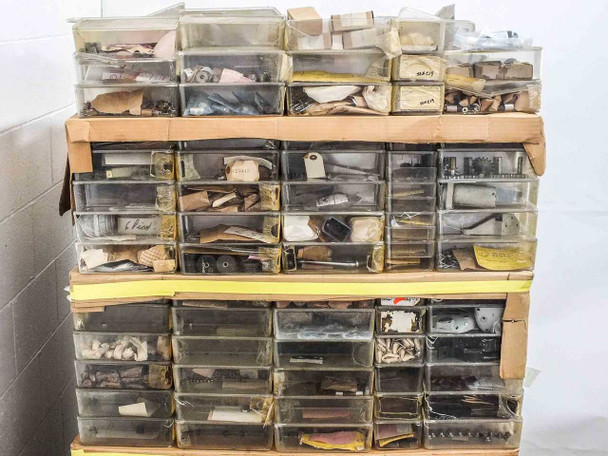Front view of stacked multi-drawer plastic organizer bins filled with assorted vintage film camera parts and hardware