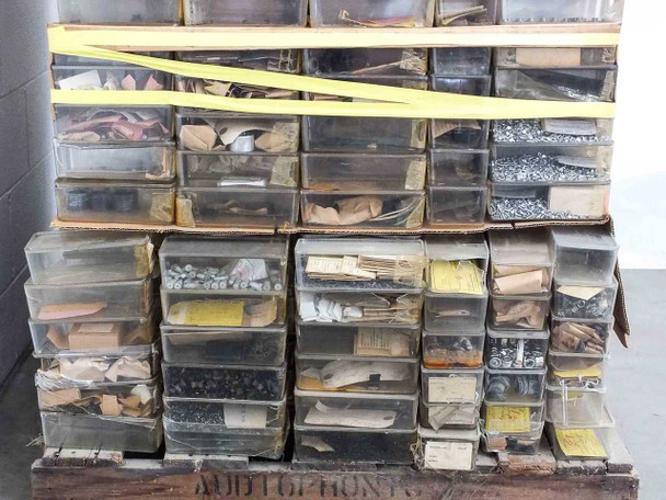 Close-up of stacked organizer drawers showing mixed small parts including screws, gaskets, springs, and mechanical components