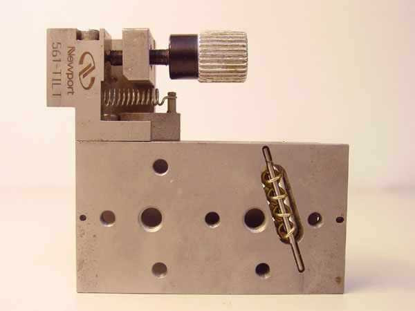 Newport 561-Tilt ULTRAlign stage – alternate end-on view showing 561-TILT Newport branding, tilt clamp spring assembly, brass ball-bearing row, and pattern of threaded mounting holes on face