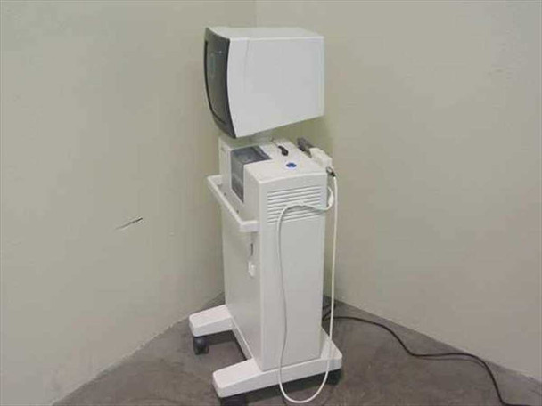 Sirona CEREC 2 dental milling machine — three-quarter left-rear view showing CRT monitor housing closed, pedestal cabinet, and power cord