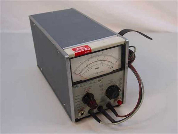 HP Hewlett Packard 410C Voltmeter — three-quarter front view showing analog meter face, function knob, range knob, and attached test leads; red asset tag on top