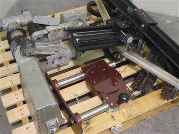 Vintage industrial camera accessories pallet — pan/tilt head with rotary base (maroon), linear rails with carriage, motor assemblies, and articulating arm components