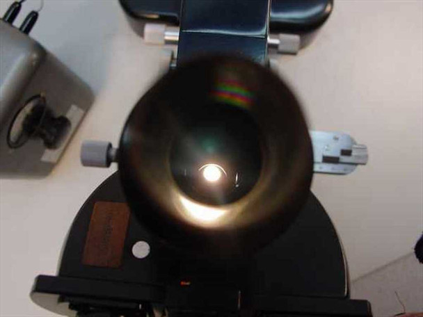 Leitz 561007 viewed from above looking down into the empty 5-position objective nosepiece, showing the illuminated condenser aperture below with rainbow light artifact
