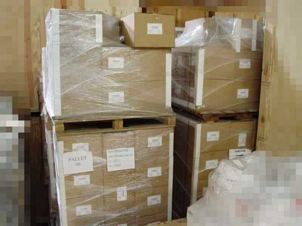 Warehouse view of palletized bulk lot inventory — multiple pallets of boxed Alpharma Optibreed SQA analyzer units wrapped in plastic