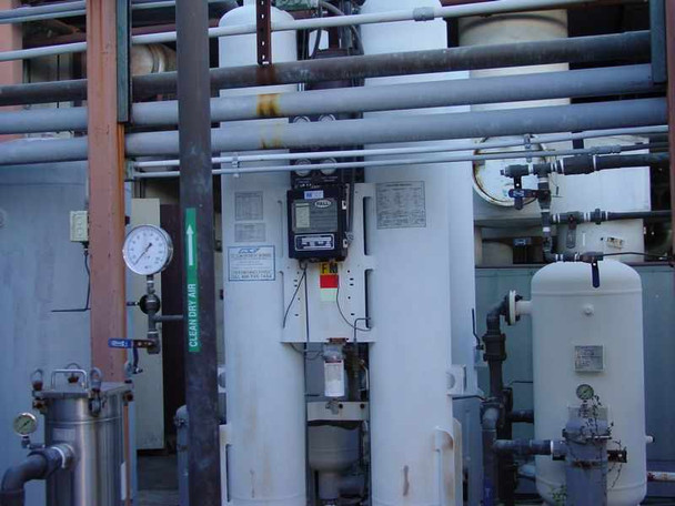White twin-tower desiccant air dryer with digital controller panel mounted on vessel, pressure gauge on Clean Dry Air labeled pipe, secondary white receiver tank — semi-enclosed outdoor installation