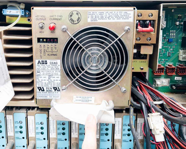 Interior view of ABB CEAG +27VDC power supply module with large cooling fan, ADJ controls, alarm LEDs, and wiring harness