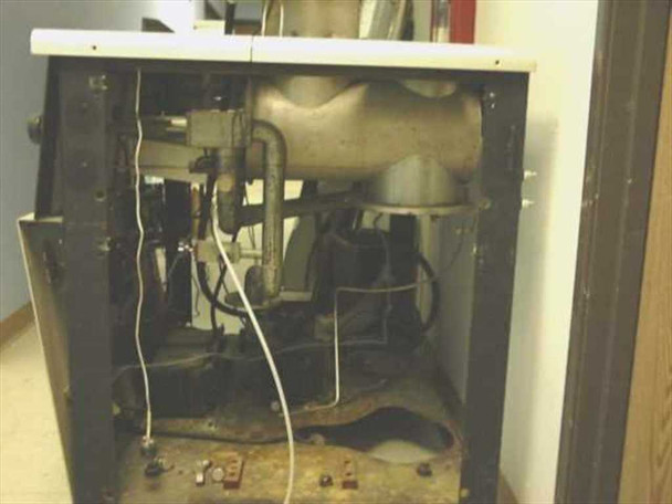 CHA-600 interior cabinet with side panel open — diffusion pump assembly with bell-shaped pump body, vacuum flanges and plumbing visible; heavy oil residue and grime on cabinet floor