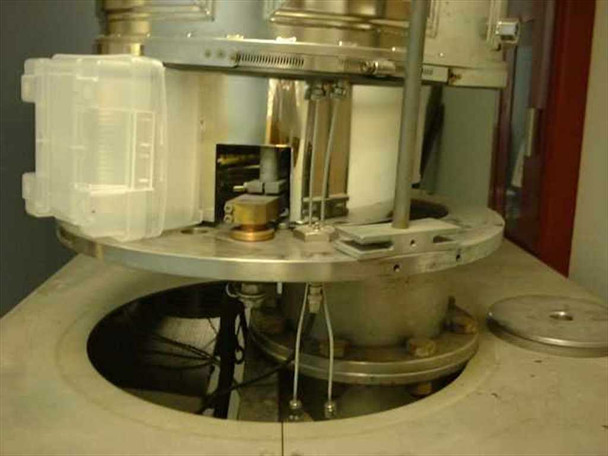 CHA-600 baseplate and planetary fixture assembly from above — large circular baseplate with central vacuum opening, clamp rings, indium evaporation source area with gold reflector and feedthrough wiring