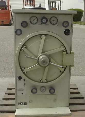 American Sterilizer Portaclave B604095-010 portable autoclave front view — door closed, wheel latch visible, pressure and temperature gauges on top panel, controls on lower left