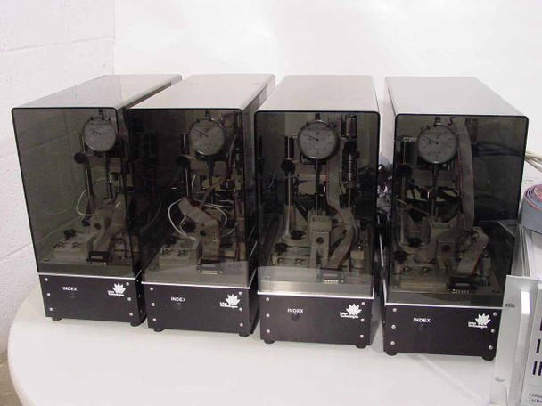 Lotus Technologies 7100 CSS tester modules – all four units side by side showing smoked acrylic enclosures with mechanical micro-gaging assemblies and dial indicators visible inside