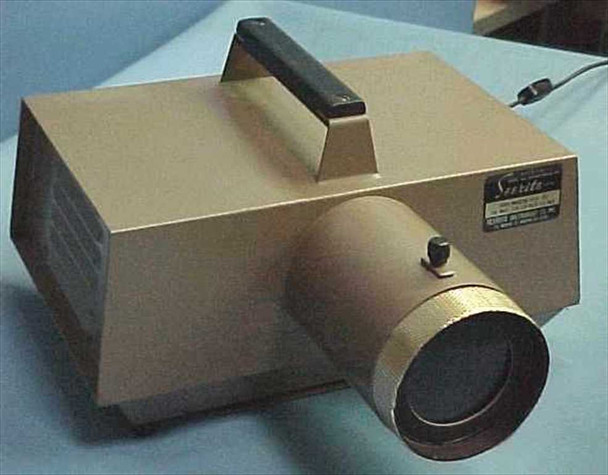 Testrite SeeRite opaque projector – three-quarter front view showing tan all-metal body, carrying handle, adjustable focus lens barrel, and SeeRite nameplate label on side