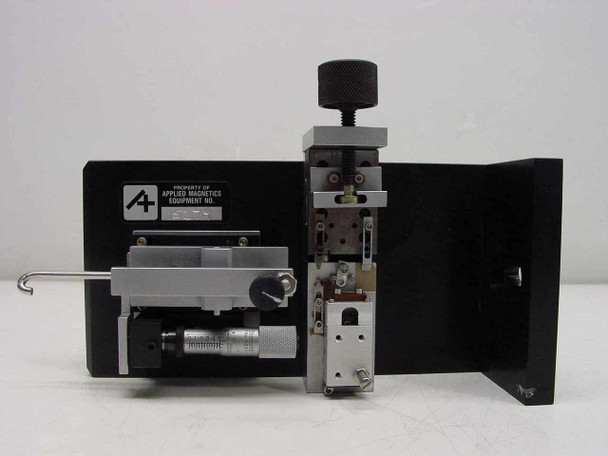 Applied Magnetics precision linear slide — rear view showing 'Property of Applied Magnetics Equipment No.' tag on end plate, full carriage assembly with clamp mechanism and micrometer adjustment visible