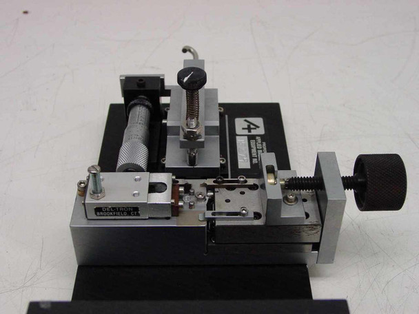 Applied Magnetics custom precision linear slide — top-front view showing micrometer adjustment barrel, spring-loaded clamp assembly, sliding carriage, and Applied Magnetics logo plate on black anodized base