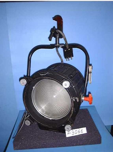 Strand Century 3501TV Castor 270 2000W Fresnel spotlight — three-quarter front view showing Fresnel lens, black housing, yoke with handle, orange adjustment knob, and white power lead