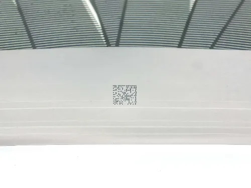 Underside close-up of Solopower CIGS solar cell showing stainless steel substrate with a QR code label — positive terminal side