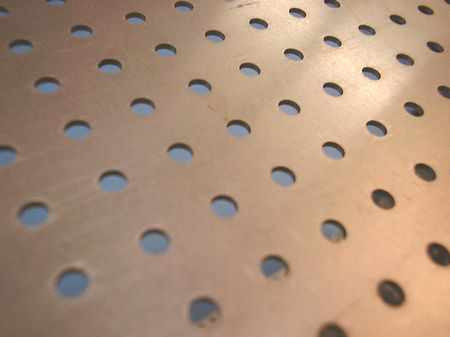 Close-up of perforated stainless steel basket surface showing evenly spaced round holes throughout the panel