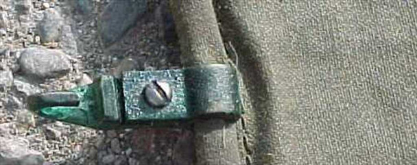 Close-up of riveted green metal clip hardware attached to M-1942 military tent wall canvas edge, showing screw fastener detail