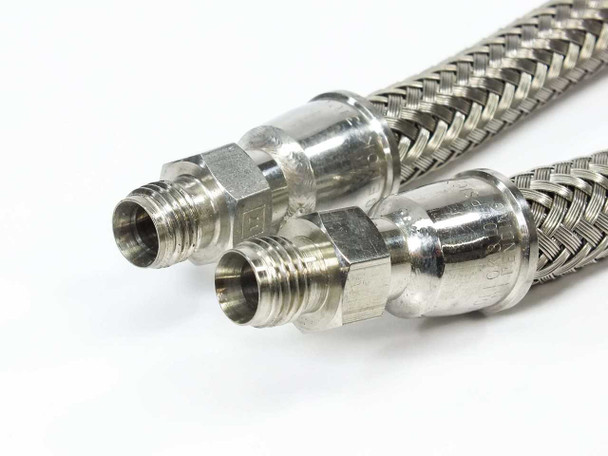 Close-up of the 1/8 inch male NPT end fittings on both Swagelok SS-FM4PM2PM2-12 stainless braided hoses showing stainless ferrules and threads