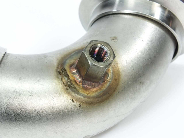Close-up of 1/8 inch female NPT electrical feedthrough hex fitting welded into elbow body showing heat discoloration and copper brazing around weld joint