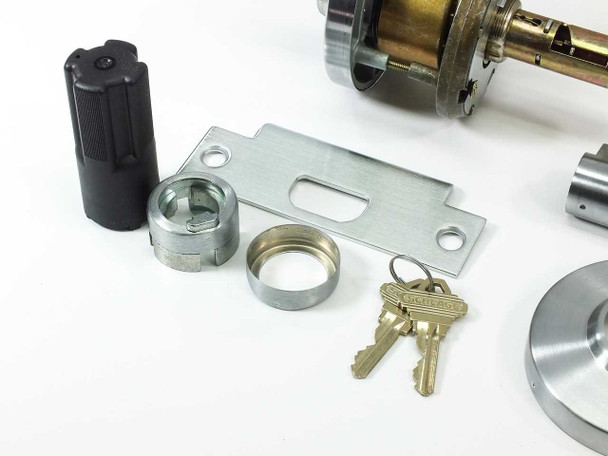 Schlage AL53PD lock hardware components: black spindle tool, cylinder ring, strike plate, and two nickel silver cut keys on ring