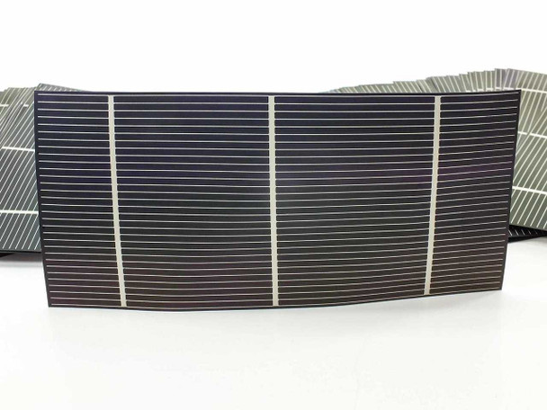 Single Solopower CIGS flexible solar cell bent to show flexibility — silver stainless steel substrate visible on underside