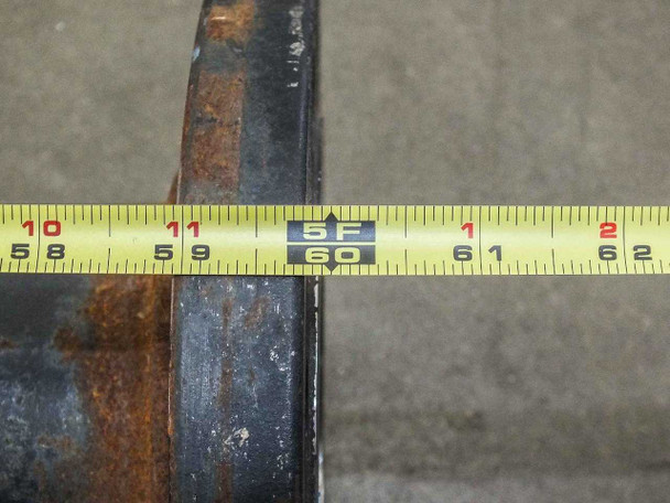 Tape measure laid against pipe showing 60-inch total length confirmation, rust-covered black steel pipe surface visible