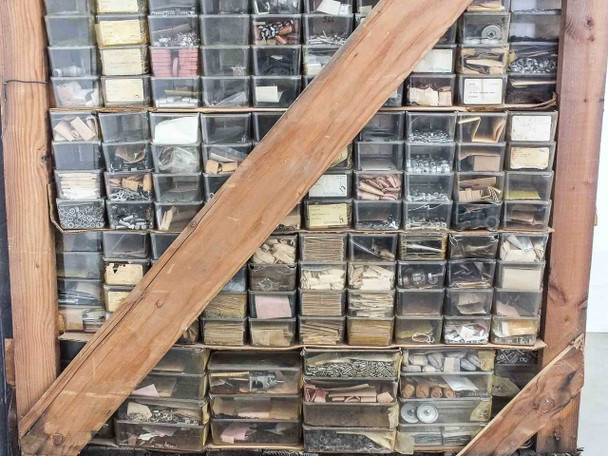 Close-up of left section of parts bins showing varied small mechanical parts and hardware in labeled drawers