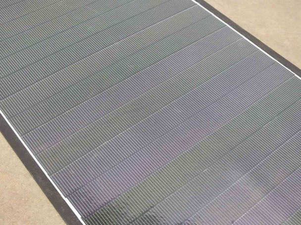 Close-up of Solopower SP1 CIGS thin-film solar cell surface showing parallel cell stripes with iridescent finish