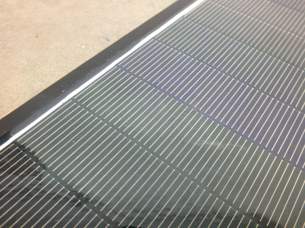 Close-up of Solopower SP1 CIGS thin-film solar cell surface showing characteristic striped cell pattern and aluminum edge frame