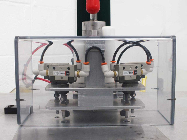Close-up of upper rivet head assembly — four SMC NVM12 pneumatic solenoid valves mounted on aluminum plate inside clear acrylic enclosure with red emergency stop button above