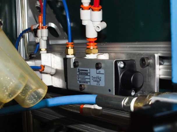 Norgren V61R5D7AXP0900 inline directional control valve close-up — mounted on aluminum extrusion rail with blue and orange push-in pneumatic tube fittings