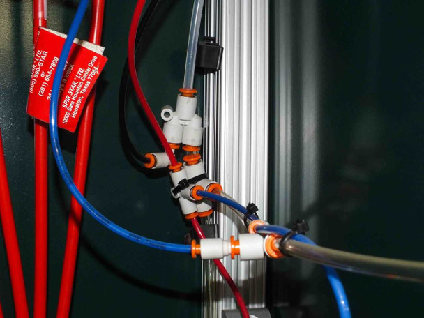 Interior pneumatic plumbing detail — red and blue Spir Star high-pressure hoses with orange-labeled safety tags routed through white push-in manifold fittings on aluminum extrusion