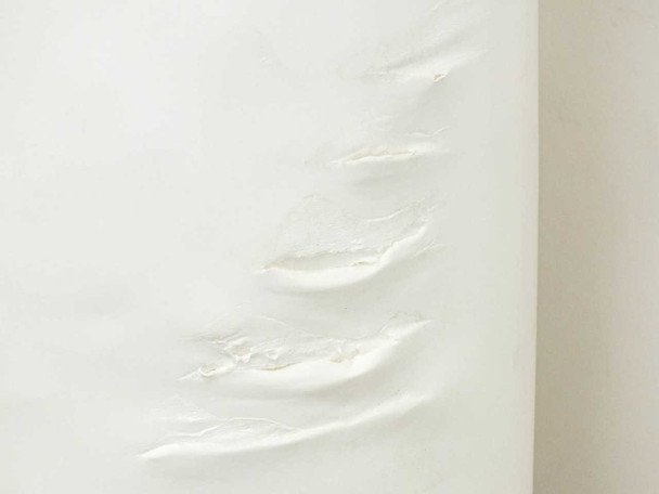 Close-up of additional surface damage on protective layer showing multiple tears and creases in the outer wrap