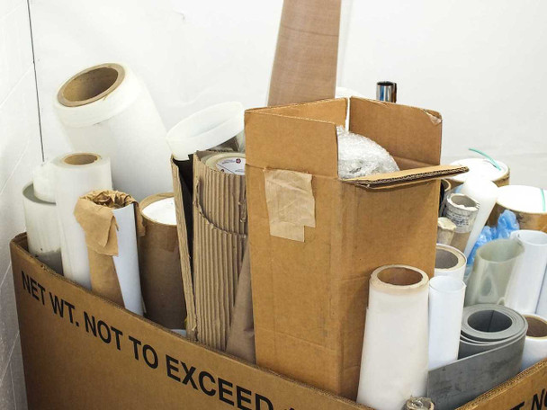 Interior view showing smaller white film rolls, an open cardboard box, gray sheet material, and additional mixed film rolls