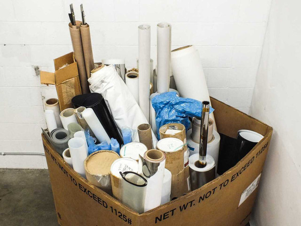 Large cardboard pallet box packed with assorted solar panel PV encapsulation film rolls — white, gray, black, and brown cardboard core rolls visible, some in blue plastic bags