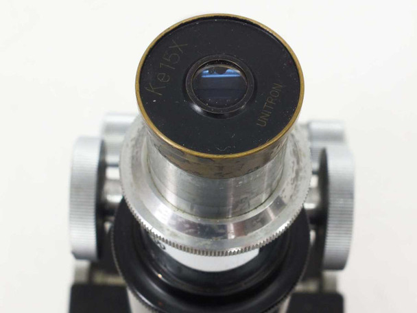 Top-down view into Unitron Ke15X eyepiece showing blue-coated lens element and 'Ke15X UNITRON' engraving on the barrel