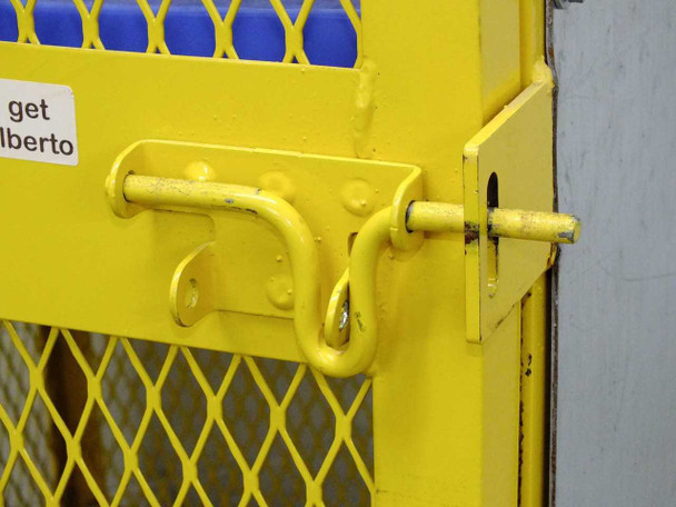 Close-up of yellow hasp-style door latch with padlock loop on lower cabinet door