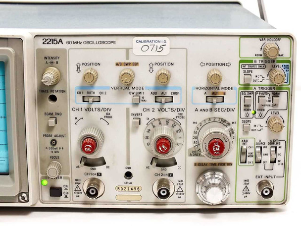 Tektronix 2215A front panel close-up showing CH1 and CH2 VOLTS/DIV knobs, Vertical Mode, Horizontal Mode, Trigger section, and Calibration ID sticker 0715