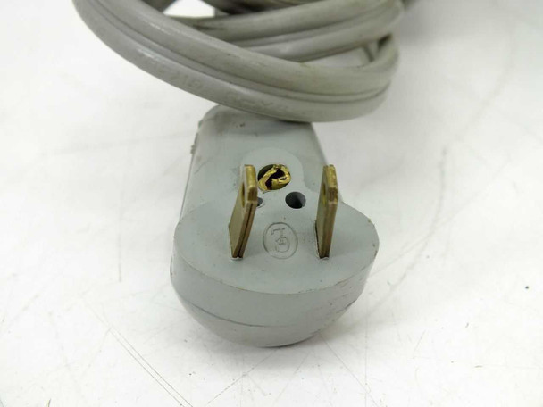 Close-up of input plug — gray 2-prong plug with two gold blade contacts and empty hole where ground pin was cut, underside view