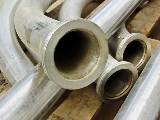 Close-up of multiple stainless steel pipe ends showing flanged bore openings and curved sections behind
