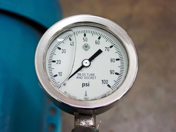 Close-up of 0-100 PSI pressure gauge with 316 SS tube and socket mounted on pump fitting