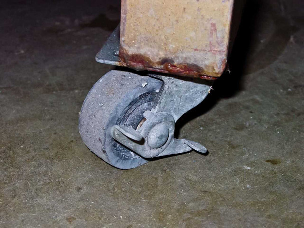 Close-up of Hobart 1R6-504 charger caster wheel showing heavy wear and surface rust on the cabinet base