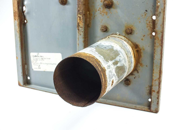Underside of mounting plate with exhauster discharge tube — heavy rust on plate and tube, LeAnCo label visible on plate surface